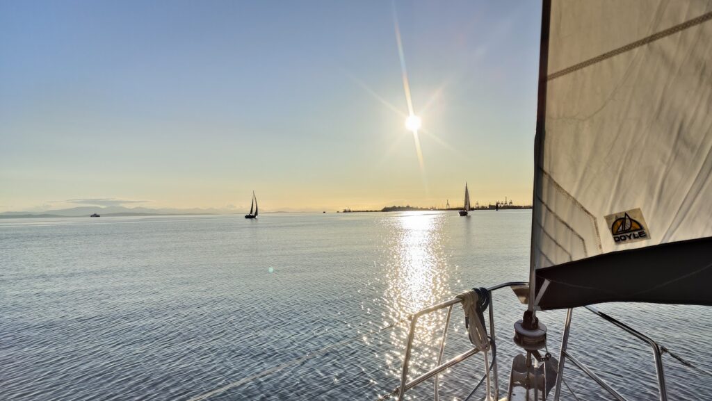 Home 8 Sailboat silhouetted against a sunset, inviting you to join LMYC and live your yachting